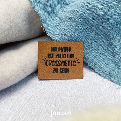 Kunstlederlabel «Niemand ist zu klein, grossartig zu sein» zum Annähen – in der Schweiz lasergraviert